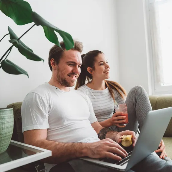 Pár sedí na gauči s notebookem